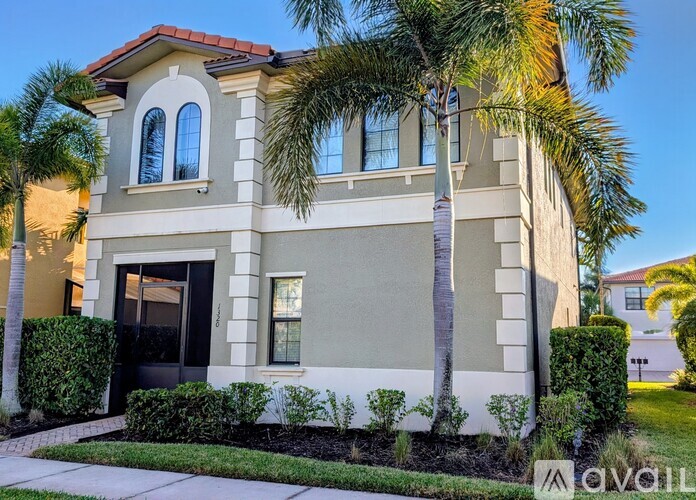 A two-story house with a red tile roof and a palm tree in front.