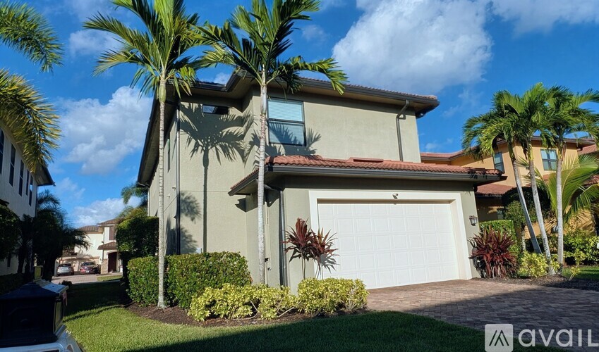 A house with a garage and palm trees in front.