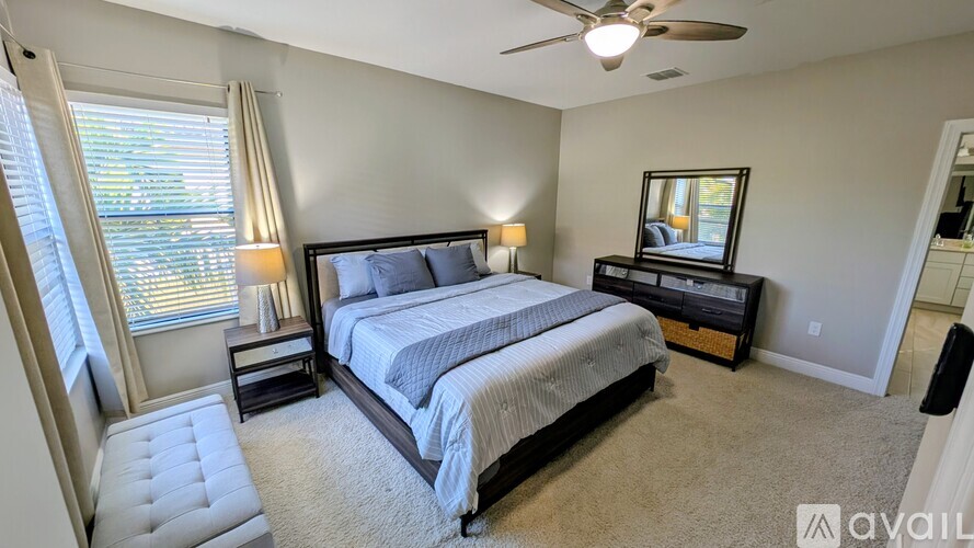 A bedroom with a large bed, a chair, and a ceiling fan.
