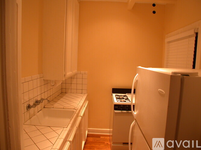 A small kitchen with a white fridge and a white sink.