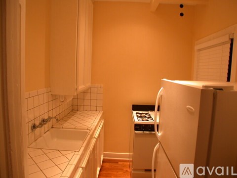 A small kitchen with a white fridge and a white sink.