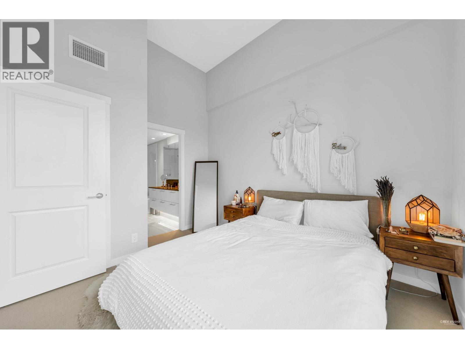A bedroom with a large bed and a wooden nightstand.