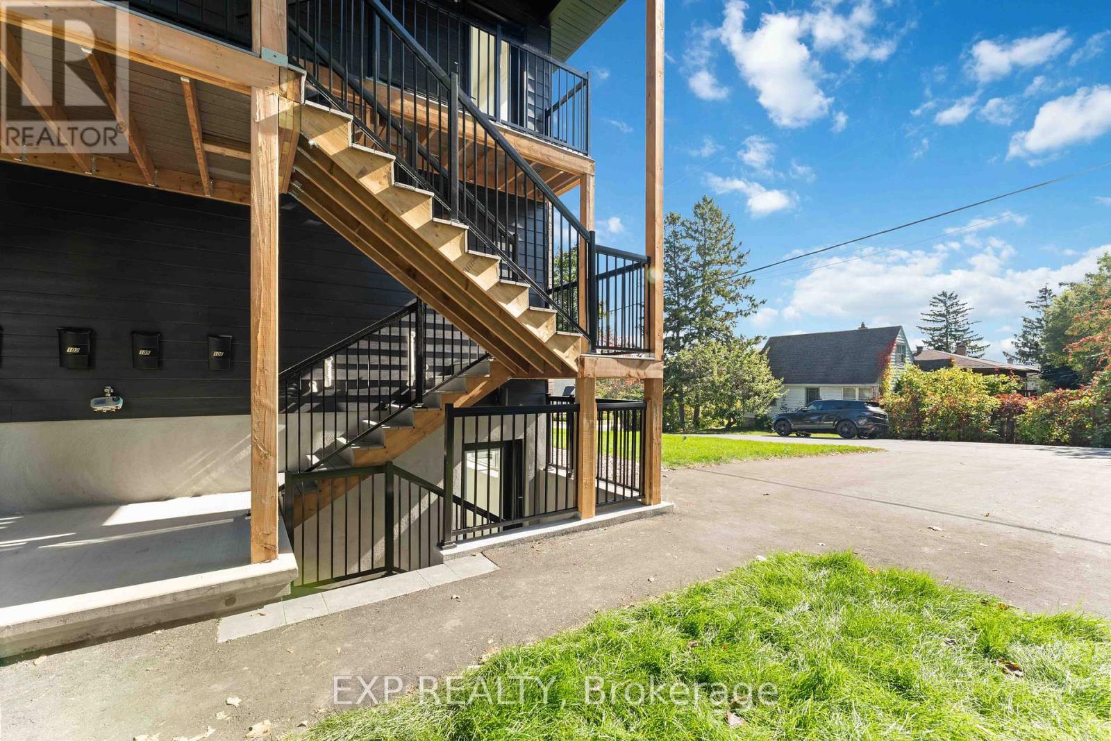 A wooden staircase with metal railings leads up to a building entrance.