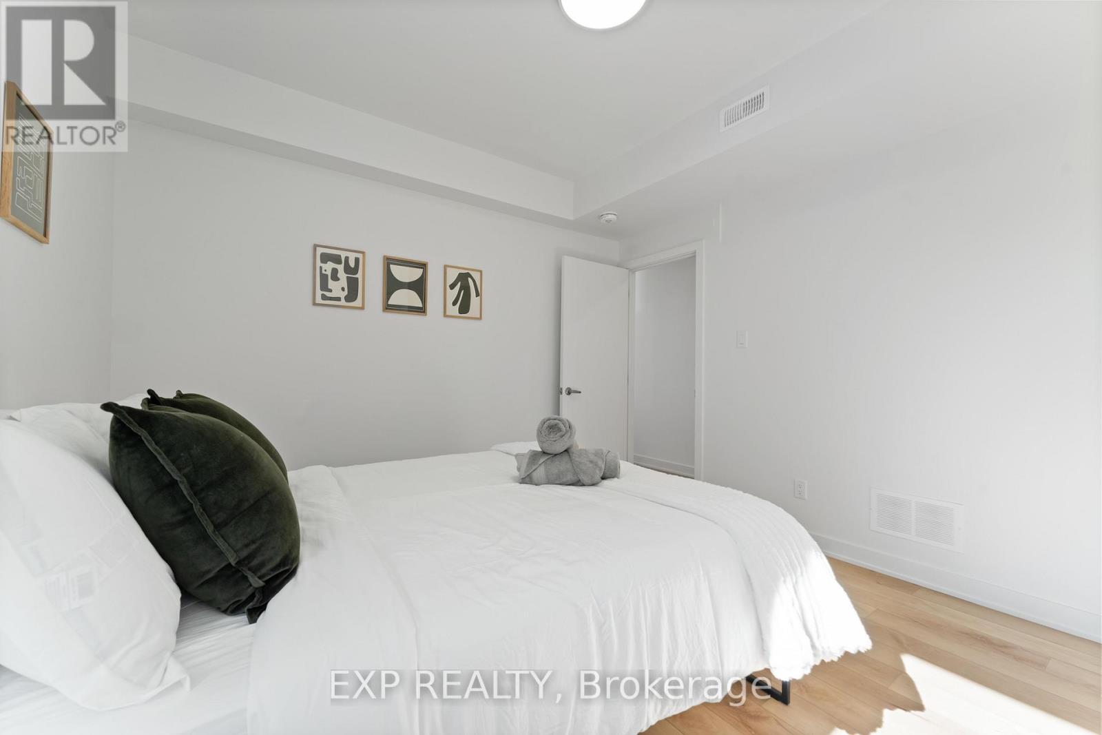 A bedroom with a white bed and a green pillow.