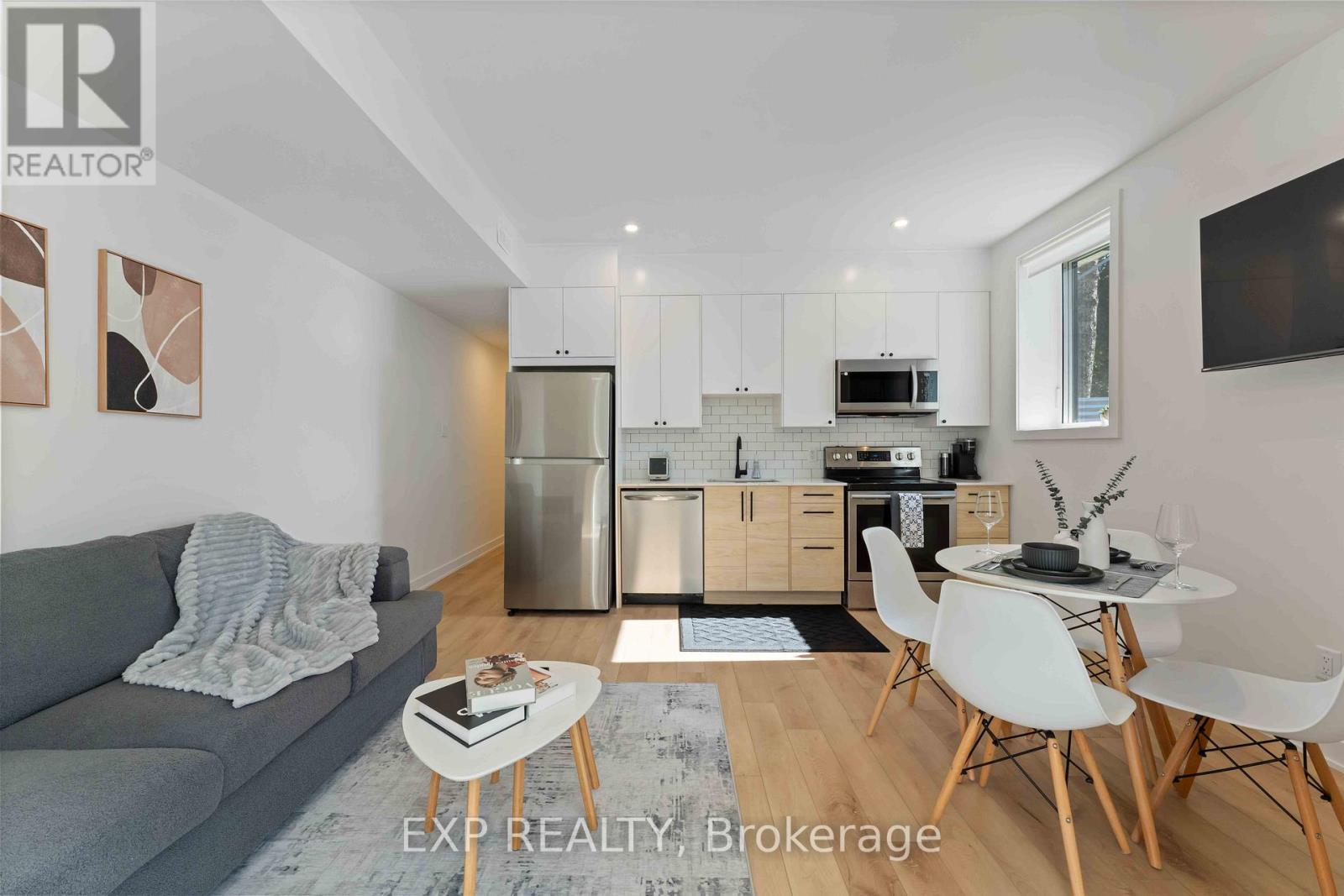 A modern kitchen with a grey couch and a dining table set for two.