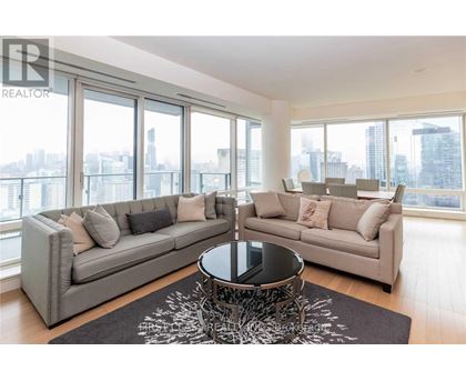 A living room with a grey sofa and a coffee table in front of a large window.