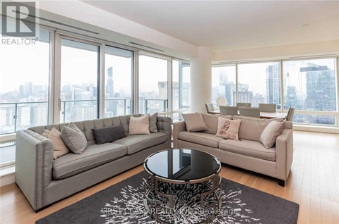 A living room with a grey sofa and a coffee table in front of a large window.