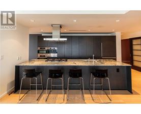 A modern kitchen with a marble countertop and bar stools.