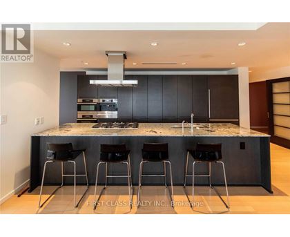A modern kitchen with a marble countertop and bar stools.