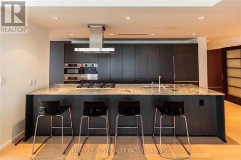 A modern kitchen with a marble countertop and bar stools.