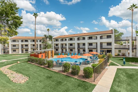 A sunny day at a poolside with a building in the background.