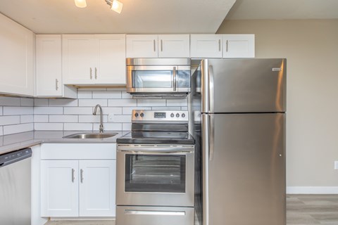 A modern kitchen with a stainless steel refrigerator, oven, and microwave.