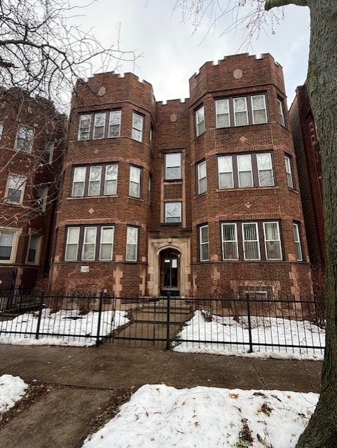 A large red brick building with a black gate in front.