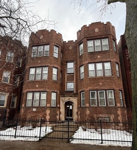A large red brick building with a black fence and snow on the ground.