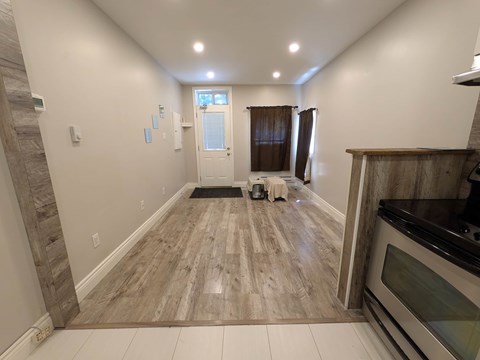 A kitchen with a wooden floor and a stainless steel oven.