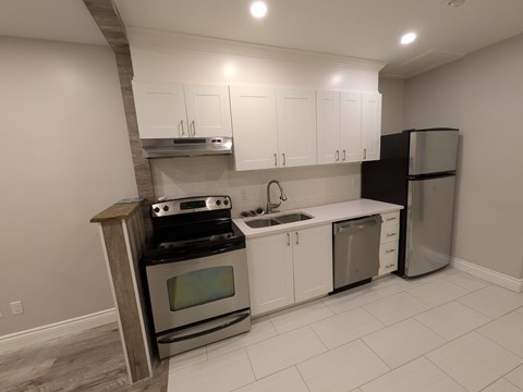 A kitchen with white cabinets and a black refrigerator.