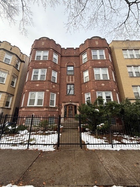 A large red brick building with a black gate in front.
