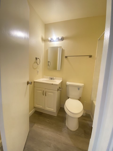 A small white bathroom with a toilet, sink, and medicine cabinet.