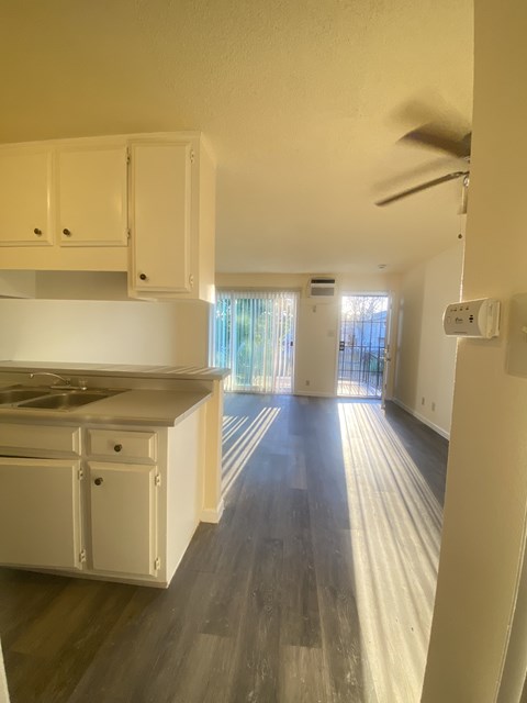 A kitchen with white cabinets and a wooden floor.