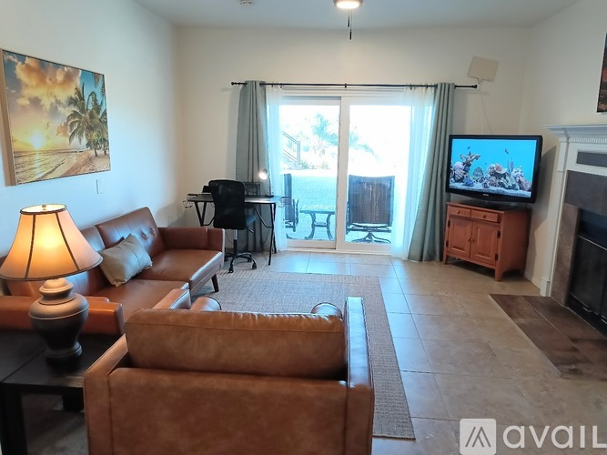 A living room with a brown couch, a lamp, a painting, a TV, and a fireplace.