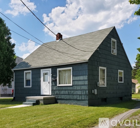A small house with a grey exterior and a white door.