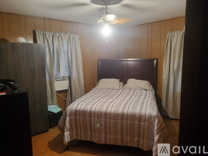 A bedroom with a bed, nightstand, and a ceiling fan.