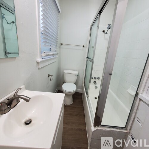 A bathroom with a toilet, sink, and shower.