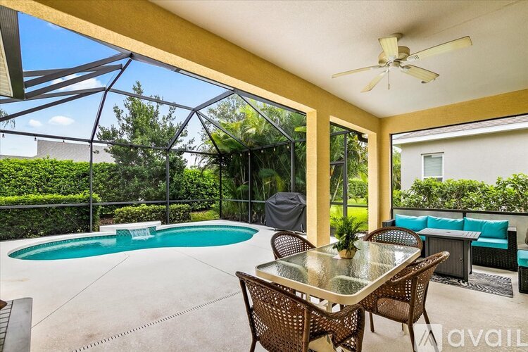 A patio with a table and chairs overlooking a pool.