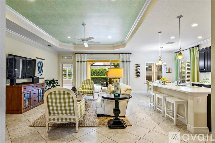 A well-lit, spacious kitchen and dining area with a checkered chair and a table with a lamp.