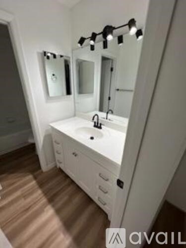 A bathroom with a sink, mirror and lighting.