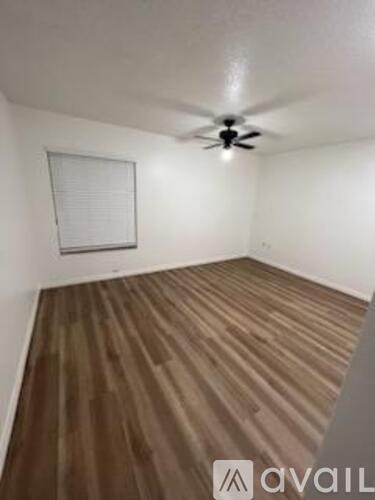A room with wooden flooring and a ceiling fan.