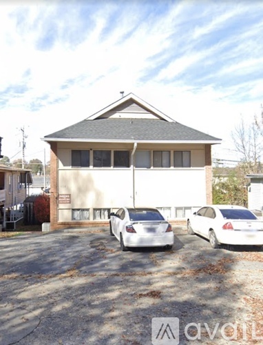 A white car is parked in front of a two-story building.