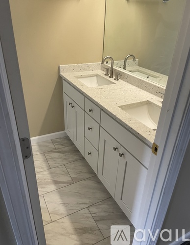 A bathroom with a white counter top and cabinets.