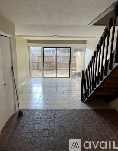 A hallway with a tiled floor and a staircase on the right.