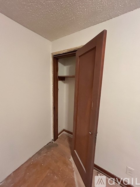 A room with a white wall and a brown door.