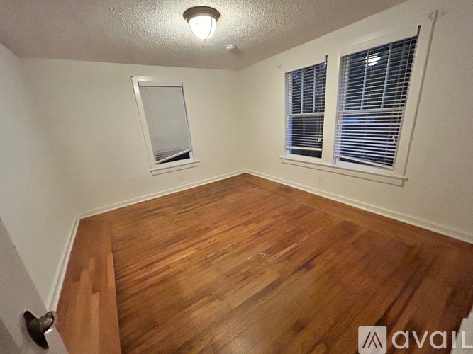 A room with wooden flooring and a window with blinds.