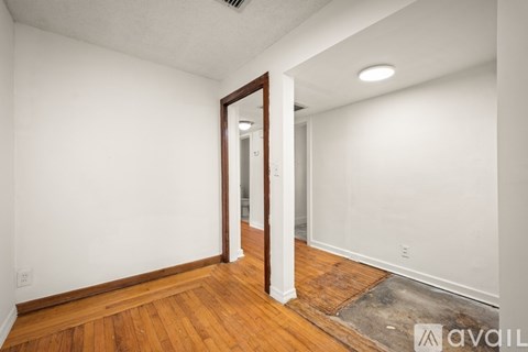 A room with wooden flooring and a window with blinds.