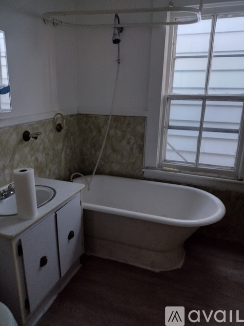 A white bathroom with a tub, sink, and window.