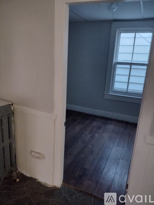 A room with a window and wooden floors.