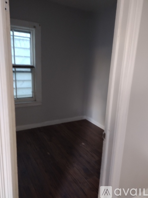 A room with a window and wooden floors.