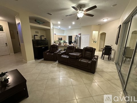 A living room with a brown leather couch and a ceiling fan.