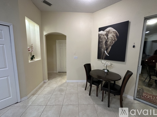 A dining room with a table set for two and a painting of an elephant on the wall.