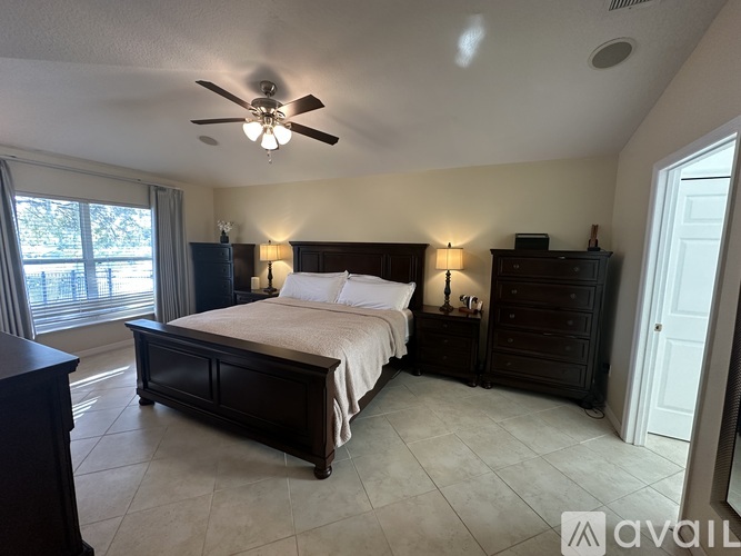 A bedroom with a large bed and a ceiling fan.