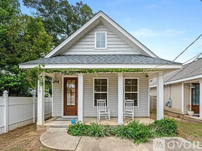 A small house with a porch and a white picket fence.