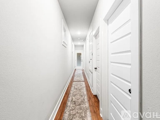 A long hallway with white doors and a patterned carpet.