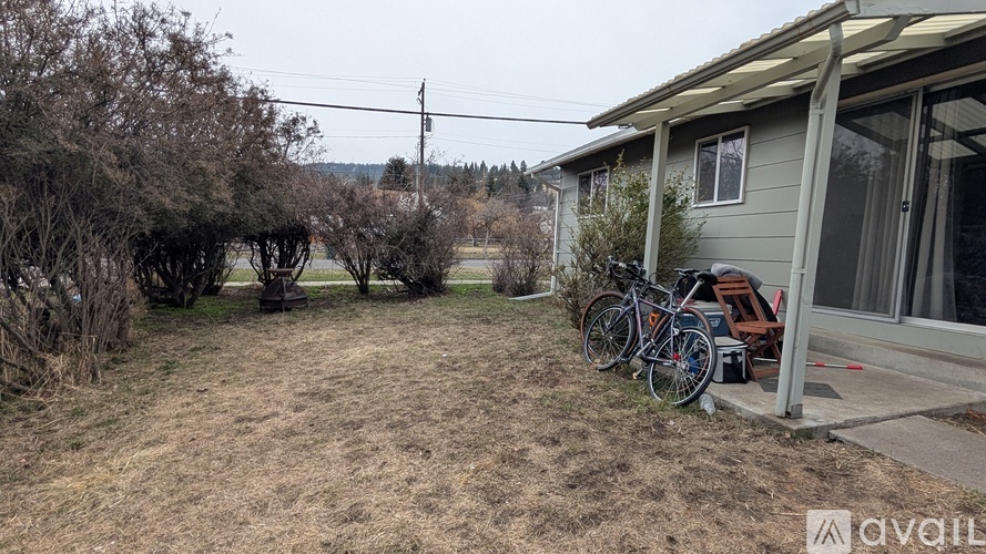 A backyard with a house, a bicycle, and a chair.