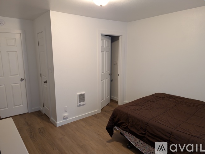 A bedroom with a bed, two doors, and a window.