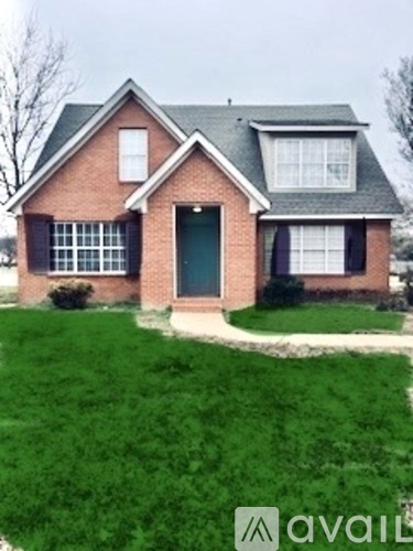 A brick house with a green door and a small front yard.