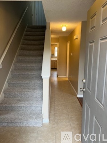 A hallway with a staircase and a door.