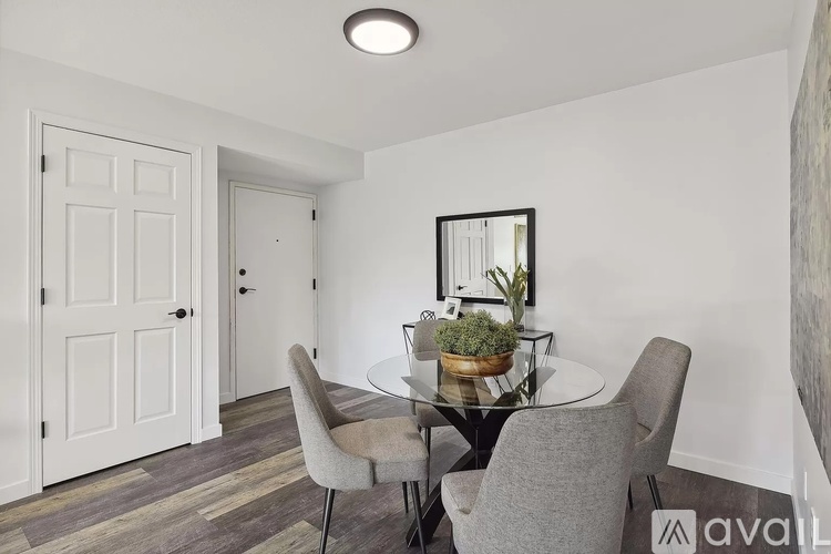 A dining room with a glass table and grey chairs.